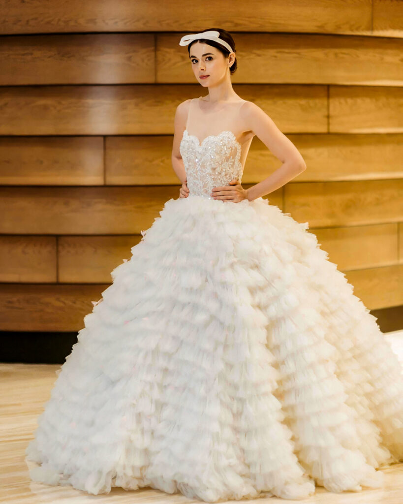 Hannah Kong Bridal Bridal gown featuring intricate beadwork top and voluminous tulle ruffled skirt